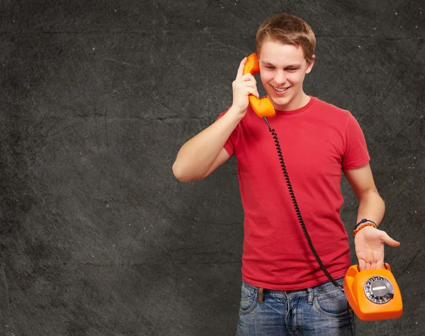 Portrait de jeune homme parlant sur téléphone vintage contre un gru — Photo