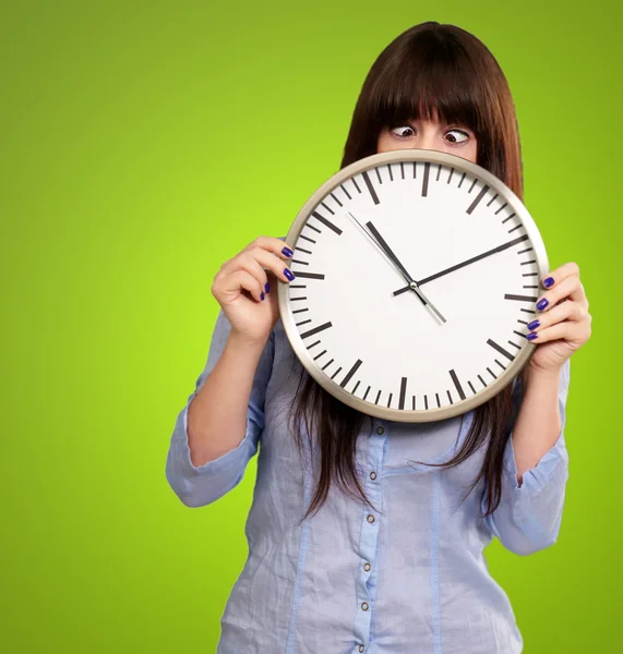 Mujer sosteniendo el reloj con ojos entrecerrados — Foto de Stock