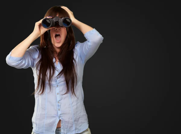 Porträt einer jungen Frau, die durch ein Fernglas blickt — Stockfoto