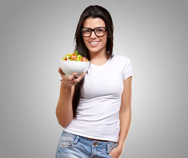 Menina mostrando uma tigela de salada — Fotografia de Stock