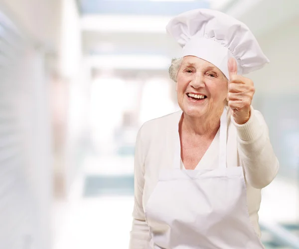 Portrait of cook senior woman doing good gesture at restaurant Stock Picture