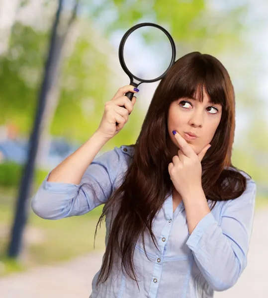 Portrait Of A Girl Holding A Magnifying Glass And Thinking Stock Picture