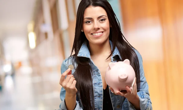 Portret van een vrouw holding een munt en spaarpot — Stockfoto