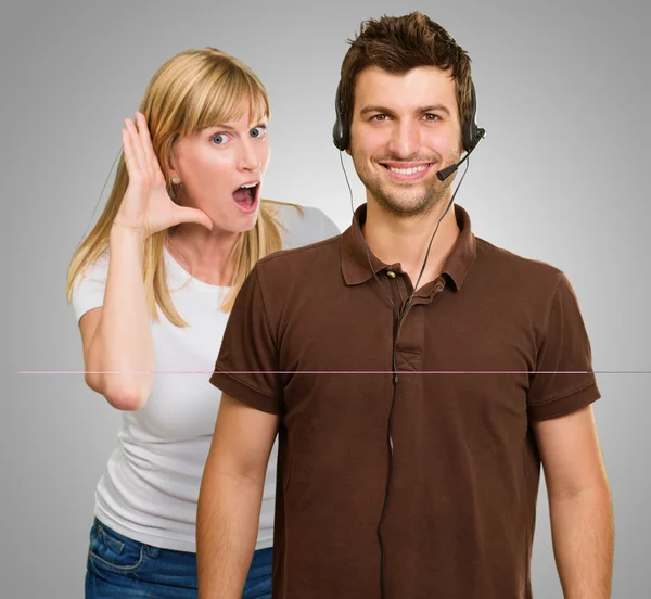 Uomo con un auricolare e donna in ascolto da dietro — Foto Stock