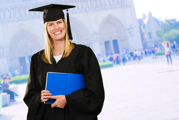 Feliz graduada mujer sosteniendo un cuaderno — Foto de Stock