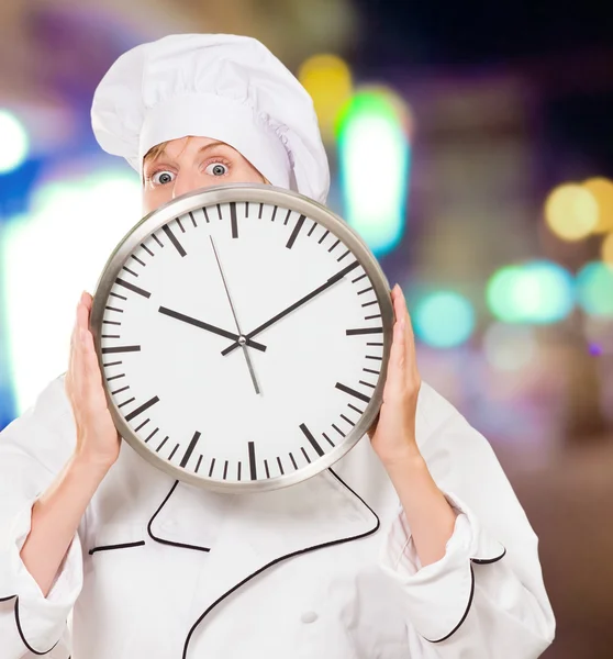 Chef feminino se escondendo atrás de um relógio — Fotografia de Stock