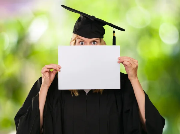 Afgestudeerde vrouw verstopt achter een blanco papier — Stockfoto