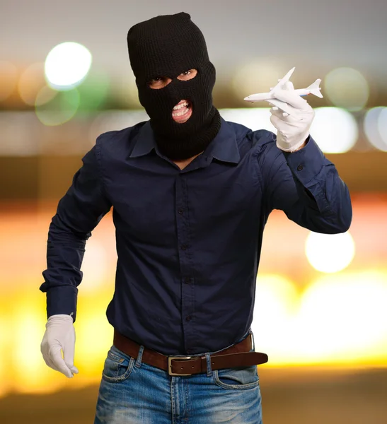 Man wearing robber mask and holding airplane miniature — Stock Photo, Image