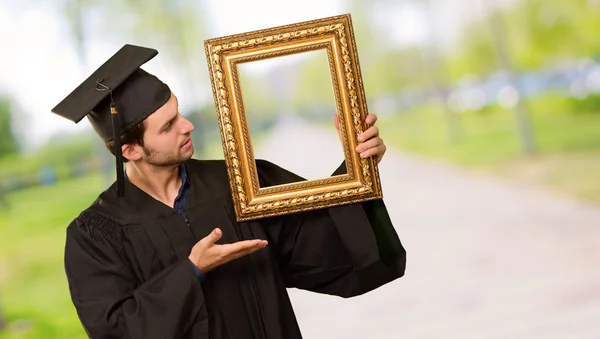 Graduate man showing a frame — Stock Photo, Image