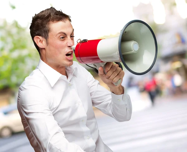 Portret van jonge man schreeuwen op megafoon — Stockfoto