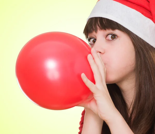 Woman wearing a christmas hat and blowing a balloon — Stock Photo, Image