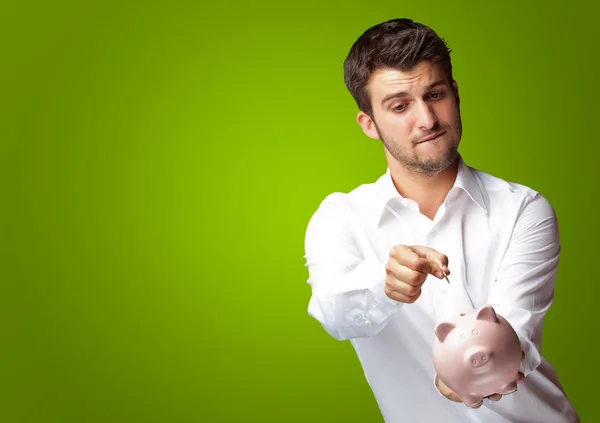 Een zakenman een munt ingebruikneming een roze piggy bank — Stockfoto