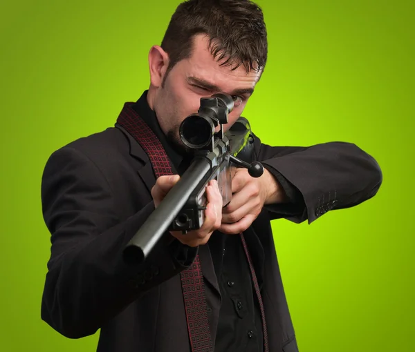 Man in suit pointing with a rifle