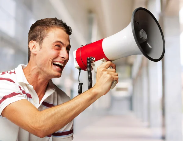 Портрет красивого молодого человека, кричащего с мегафоном — стоковое фото