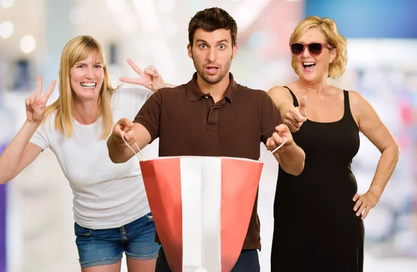 Man Holding Shopping Bag In Front Of Two Happy Women — Stock Photo, Image