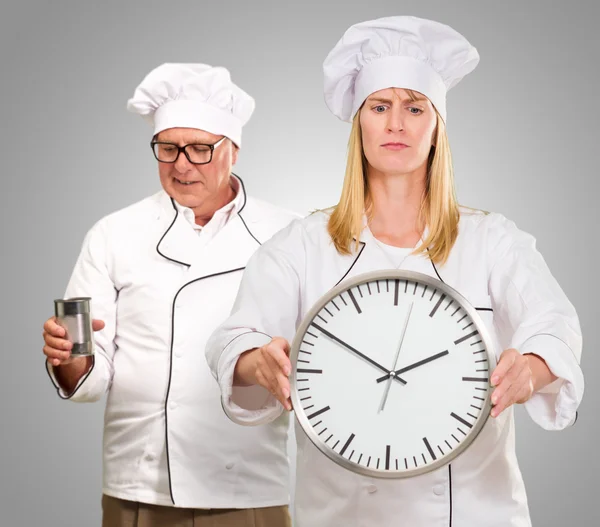 Chef femenino que sostiene el reloj delante de Chef masculino —  Fotos de Stock