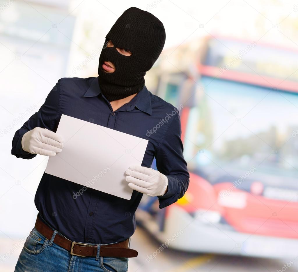 Man wearing a robber mask showing a blank paper