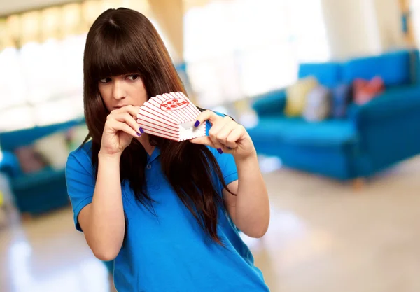 Girl looking through empty popcorn packet — Stock Photo, Image