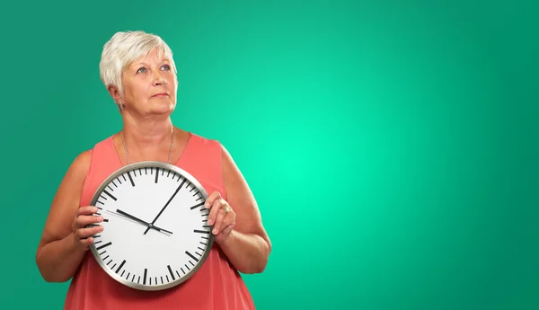 Mujer mayor sosteniendo un reloj — Foto de Stock