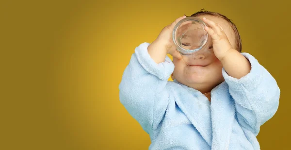 Baby boy wearing a bathrobe and holding a glass — Stock Photo, Image