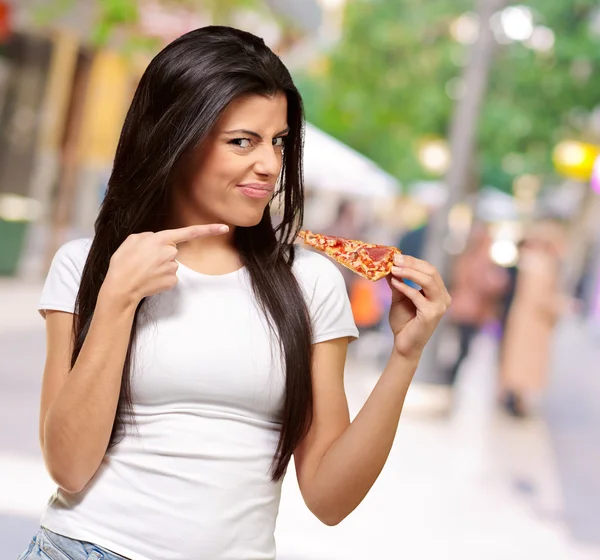 Retrato de una mujer joven comiendo un pedazo de pizza —  Fotos de Stock