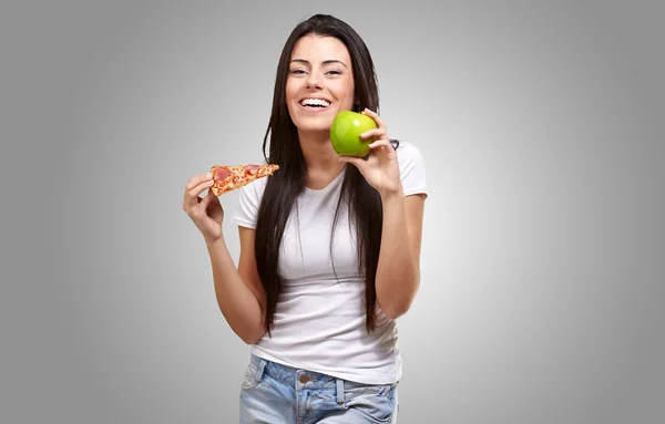 Mujer sosteniendo un pedazo de pizza y una manzana — Foto de Stock