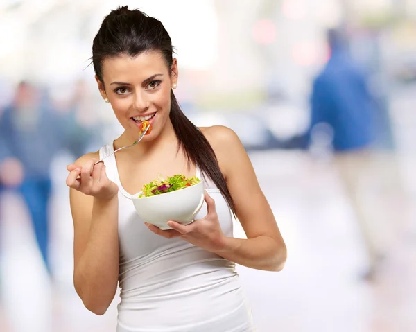 Jovem segurando e comendo salada — Fotografia de Stock