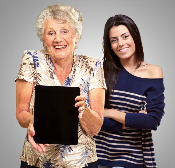 Seniorin hält digitalen Tisch vor junge Frau — Stockfoto