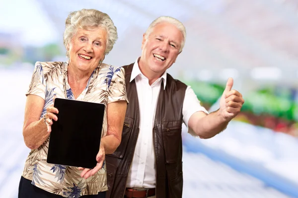 Feliz casal sênior segurando tablet digital — Fotografia de Stock