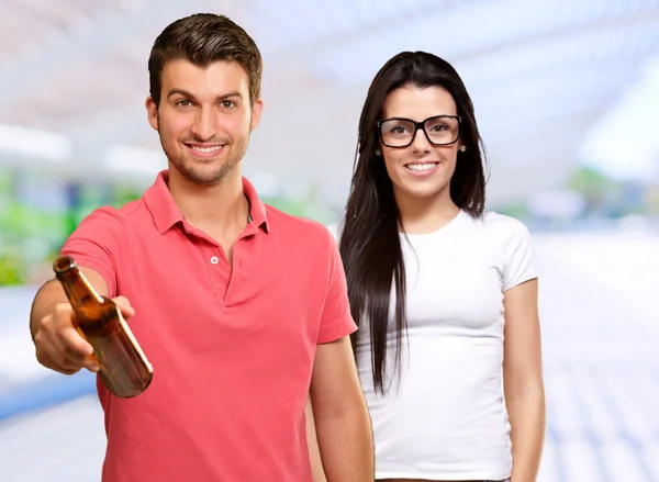 Mutlu kadın önünde alkollü şişe tutan genç adam — Stok fotoğraf