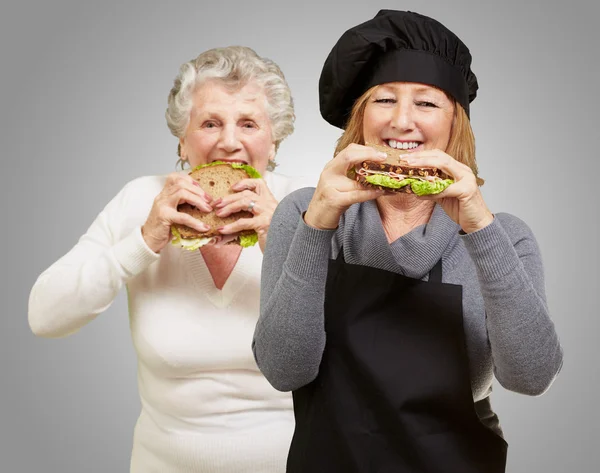 Mutlu kadın aşçı yemek sandviç — Stok fotoğraf