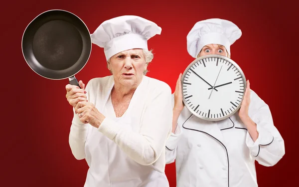 Twee vrouwelijke chef-kok bedrijf steelpan en klok — Stockfoto