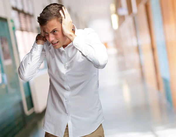 Portret van een jonge man die betrekking hebben op zijn oren met hand — Stockfoto