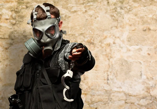 Soldaat met een gasmasker houden handboeien — Stockfoto