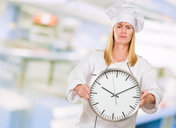 Köchin hält Uhr — Stockfoto