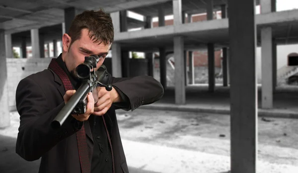 Mannen i kostym pekar med ett gevär — Stockfoto