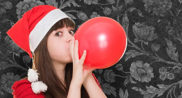 Femme portant un chapeau de Noël et soufflant un ballon — Photo