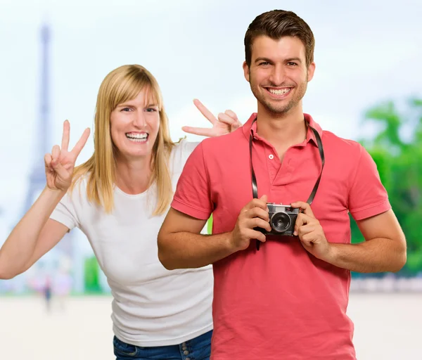 身振りで示すこと女性の前でカメラを保持している幸せな若い男 — ストック写真