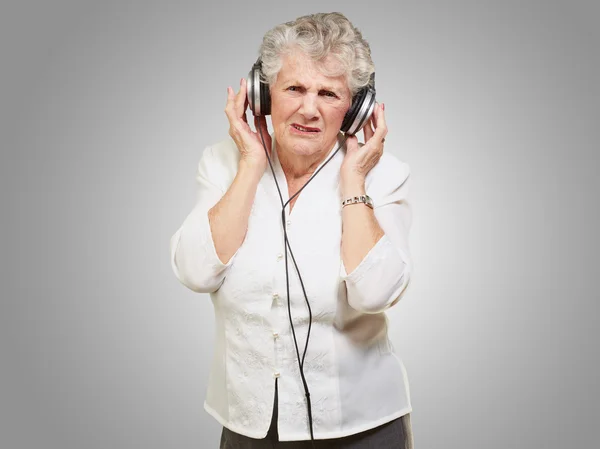 Retrato de mujer mayor escuchando música sobre fondo gris —  Fotos de Stock