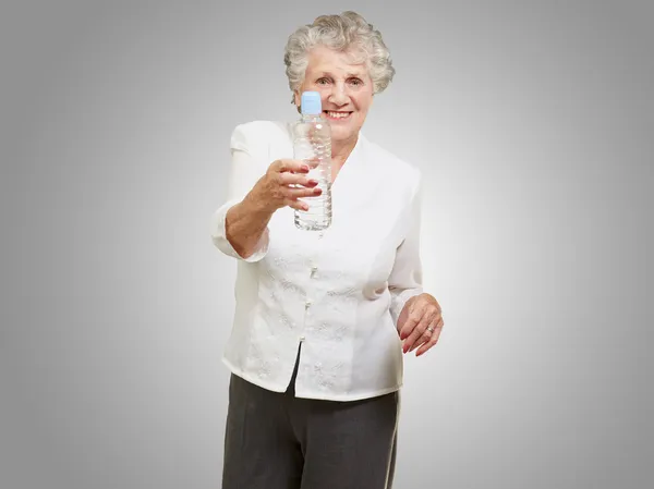 Portrait d'une femme âgée en bonne santé tenant une bouteille d'eau au-dessus du gre — Photo