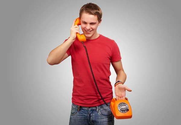 Porträt eines jungen Mannes, der mit einem alten Telefon über einem grauen Bac spricht — Stockfoto