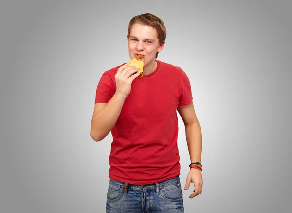 Genç adam yemek pizza gri arka plan üzerinde portresi — Stok fotoğraf