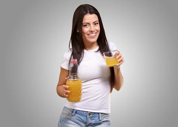 Portræt af ung pige drikker appelsinjuice mod en grå ryg - Stock-foto