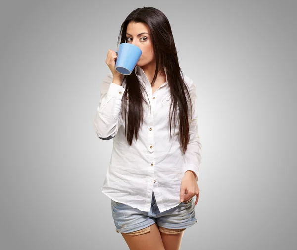 Portrét mladé ženy pití šedé pozadí — Stock fotografie