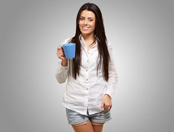 Chica joven sosteniendo taza sobre fondo gris — Foto de Stock