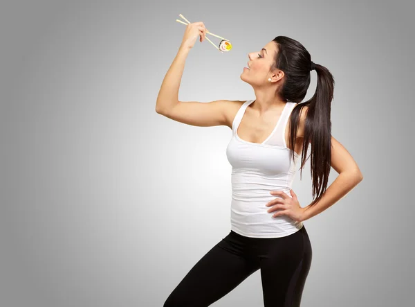 Молодая красивая женщина ест суши на сером фоне — стоковое фото