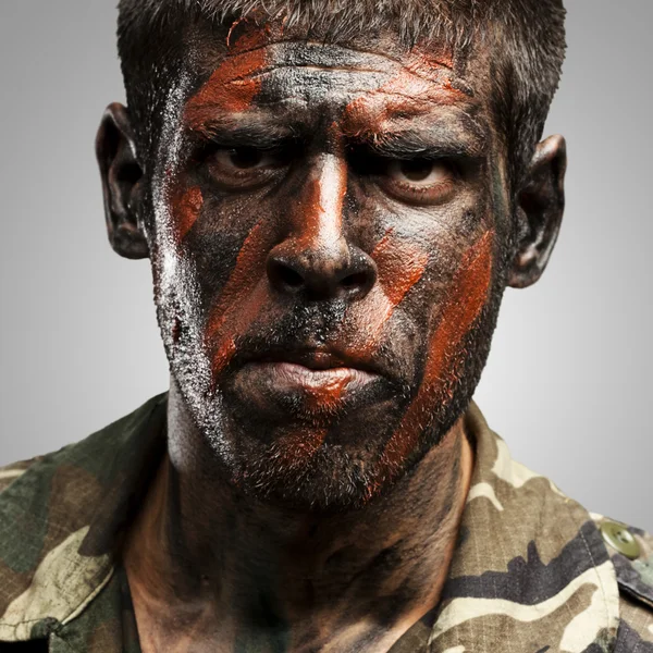 Jovem soldado com pintura de camuflagem parecendo muito sério sobre gr — Fotografia de Stock