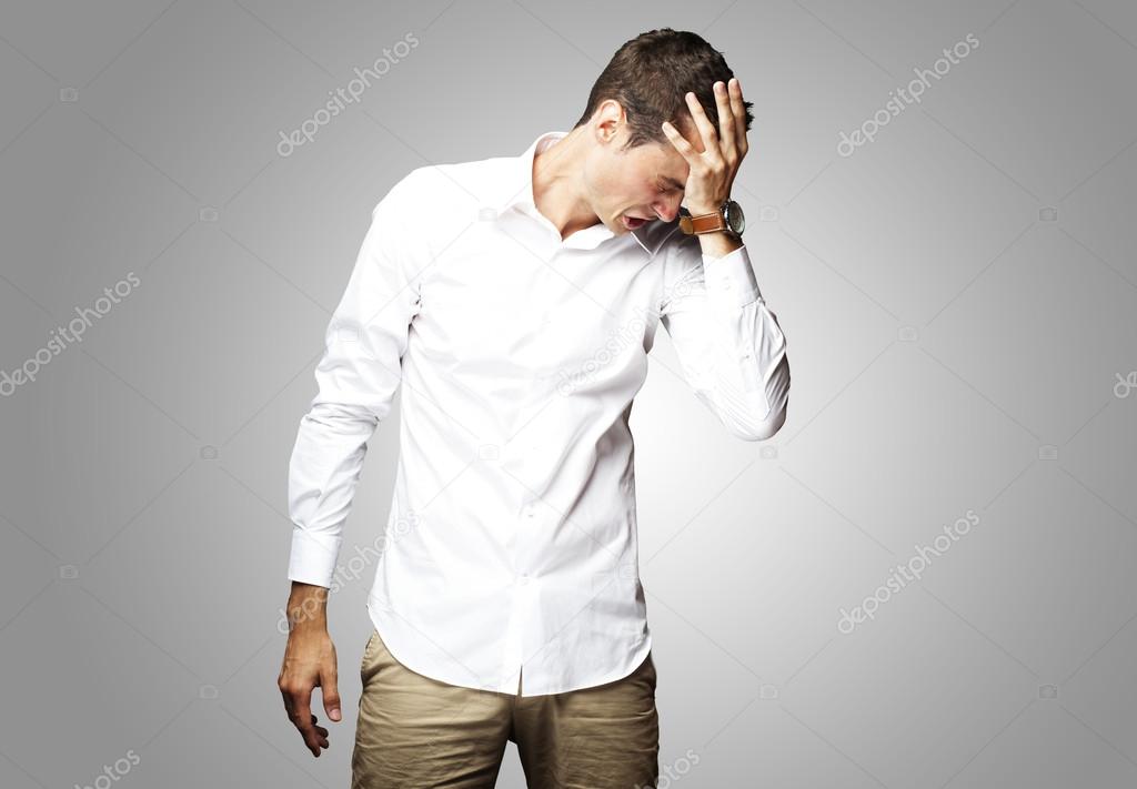 Angry young man doing frustration gesture over grey background