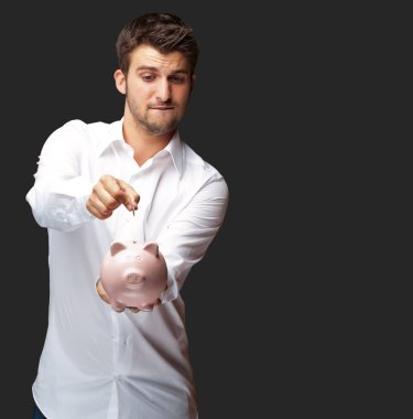 pembe bir kumbara bozuk para koyarak bir işadamı