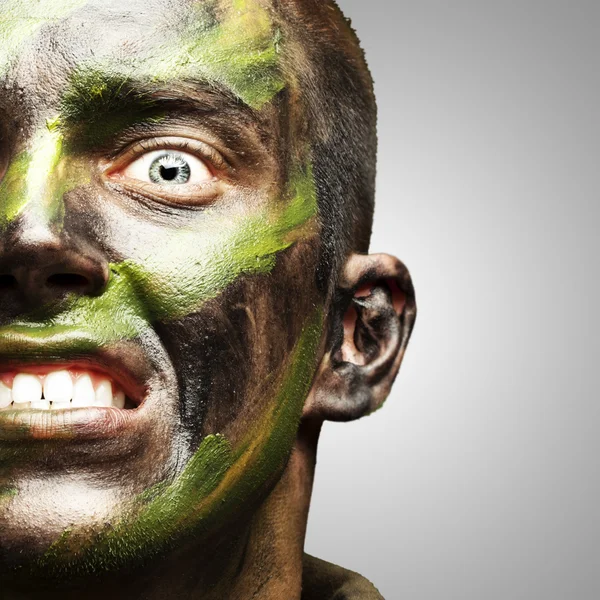 Young soldier face with camouflage paint over grey — Stock Photo, Image